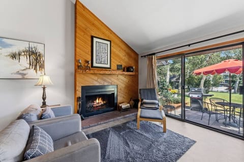 Living room with fireplace, vaulted ceilings, large windows, and walkout patio