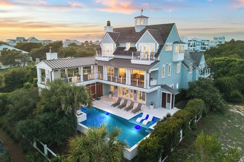 A stunning coastal retreat with multiple stories, a private pool with lounge chairs, and spacious balconies surrounded by lush tropical vegetation and ocean breezes.