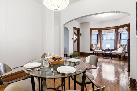 Bright dining and lounge area with hardwood floors, original wood trim, and a cozy sitting nook.