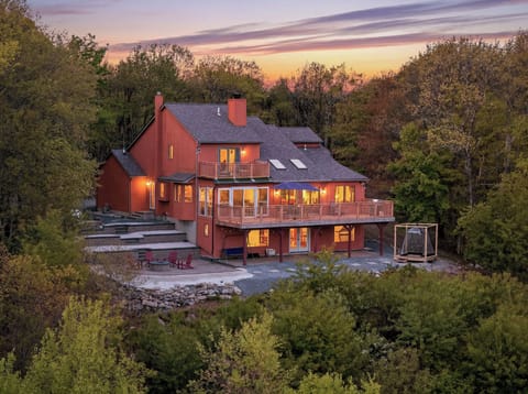 Sunset over a private wooded retreat with expansive decks, outdoor gathering spaces, and peaceful mountain-style charm.