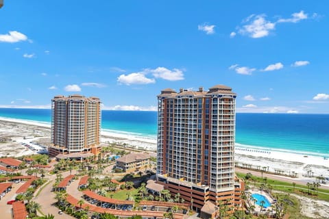 Beachfront resort towers rise above pristine white sands and turquoise waters, offering a stunning coastal location surrounded by tropical landscaping and convenient amenities.