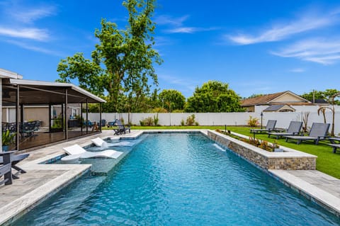 Resort-style private pool with sun shelf loungers and spacious backyard oasis perfect for relaxing and entertaining.