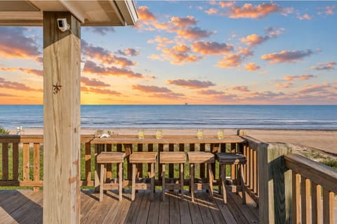 Expansive beachfront deck with wooden rocking chairs and unobstructed Gulf Coast views ideal for outdoor lounging, family gatherings, and enjoying ocean breezes.