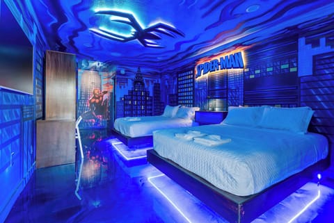 Experience a themed stay in this spider-man inspired room with cityscape murals and ambient blue lighting.