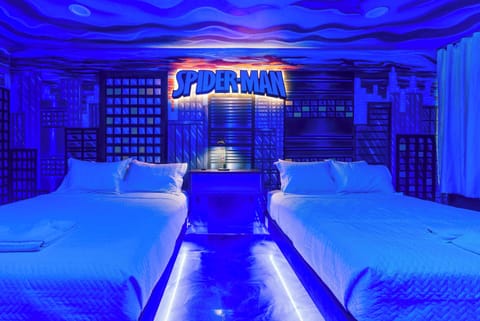 spider-man themed room with cityscape mural and two queen beds