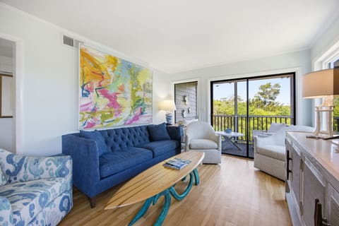 Relax in this bright coastal living room with cozy seating and peaceful balcony views