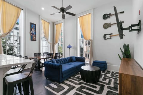 Relax in a music-filled living room with tall windows, modern comforts, and vibrant local artistic flair inspired by New Orleans culture.