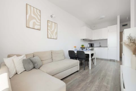 A cozy living room corner with a sofa and minimalist décor. The room feels warm, tidy, and well-lit.