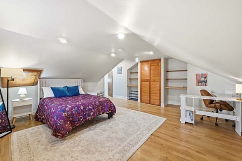 Inviting bedroom w/ plum-toned bedding, wood floors & a handy desk nook.