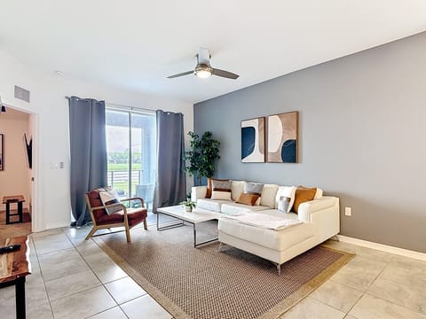 Bright and inviting living room with comfortable seating, natural light, and balcony access.