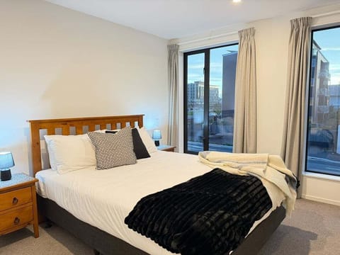 Upstairs bedroom, queen bed, stadium across the road — this is the view at dusk, both lamps on, throws layered for winter.
