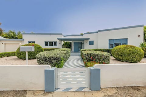 Modern single-story vacation home with landscaped garden and gated entrance, set in a sunny coastal area perfect for relaxed getaways.