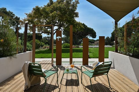 Your private shaded terrace — two green chairs, a small table, and garden greenery on all sides