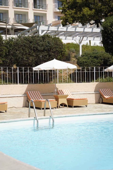 Wicker loungers with orange-striped cushions arranged along the shimmering poolside