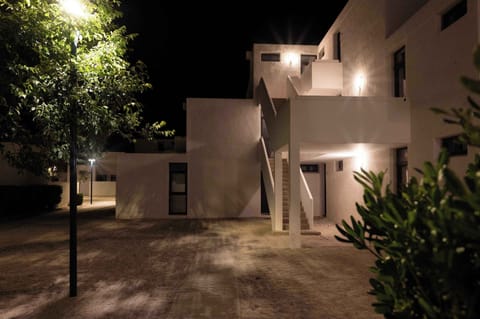 The residence at night — white facades glowing under the stars, peaceful and car-free.