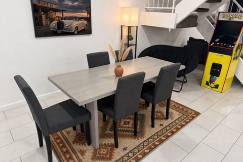 Bright dining area with seating for six and arcade game