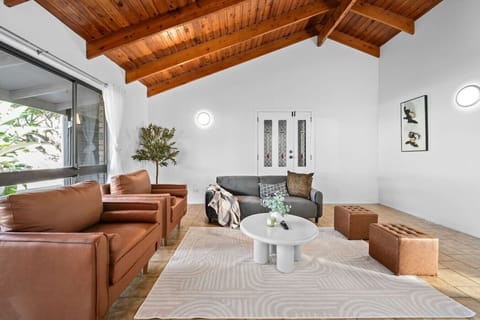 Imagine unwinding with your loved ones in this warm, character-filled living room — rich timber ceilings, lush greenery, and a laid-back elegance that instantly feels like home.