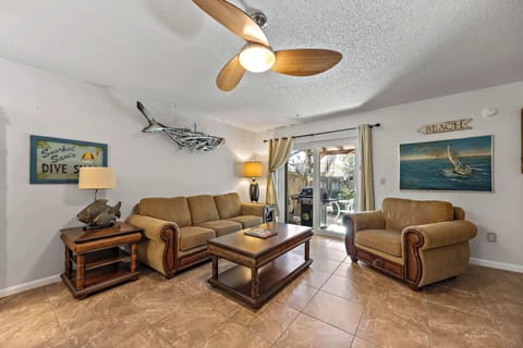 Cozy living room with comfortable seating and a ceiling fan overlooking a patio area.