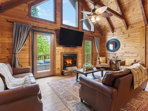 Cozy cabin living with vaulted wood ceilings, a fireplace, and direct deck access for relaxing mountain downtime.