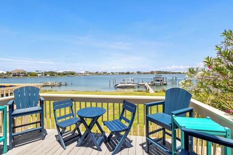 Waterfront views stretch across calm Sabine Bay waters from this inviting north facing balcony off of the living room, where colorful seating awaits as boats drift by and distant shores complete the coastal scene.