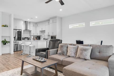 Spacious open-concept living area with a sleek sectional, elegant decor, and direct flow into the modern kitchen.