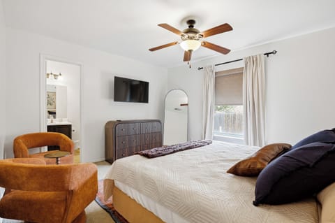 King primary bedroom with a ceiling fan, soft bedding, and private ensuite access. Spacious layout with closet storage and warm, welcoming decor throughout.