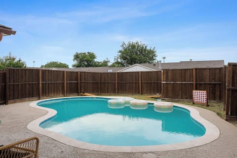 The pool area features comfortable floating loungers and a secure fence for added privacy. Ideal for enjoying sunny days.