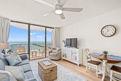 Full-size couch and upholstered chair fill this oceanfront living room, framed by floor-to-ceiling windows and a smart TV.Full-size couch and upholstered chair fill this oceanfront living room, framed by floor-to-ceiling windows and a smart TV.