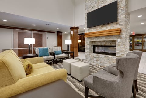 Cozy lobby seating area featuring a decorative fireplace and television.