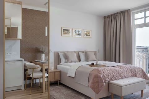 Bright studio with a comfortable double bed, seating area, and direct access to a private balcony.