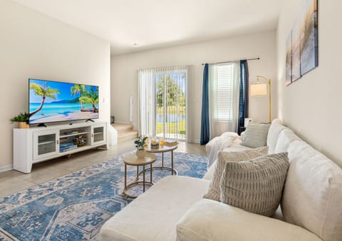 Bright coastal-style living room with Smart TV and direct access to a lake-view 