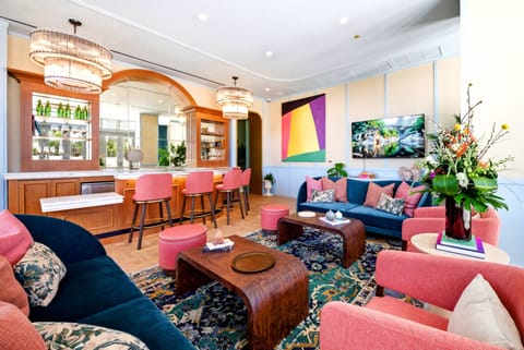 Experience a vibrant living area with bold pink sofas and warm wooden accents. The stylish decor features a beautifully patterned rug and striking artwork, creating a welcoming space perfect for relaxation and conversation.