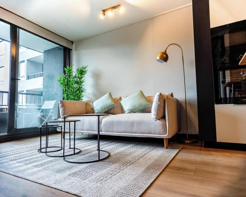 Relax in this stylish living room with a cozy sofa, chic decor, and abundant natural light from large windows.