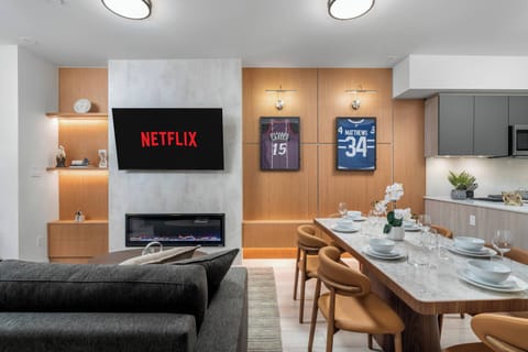 Open-concept living and dining area with Smart TV, fireplace, and modern kitchen.
