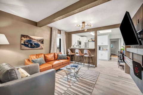 Bright open-plan living room w/ cozy orange sofas & a TV ready for movie nights.
