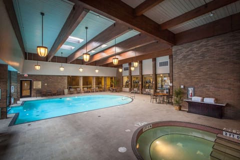 Indoor pool area with whirlpool, tables, towels, and brick walls