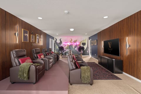 Villain-themed movie theater room with reclining seats, pink accents, wall art, 