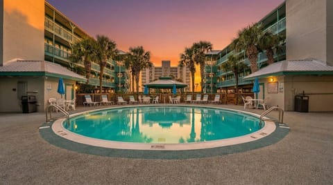 Resort-style pool courtyard with palm trees and stunning sunset views
