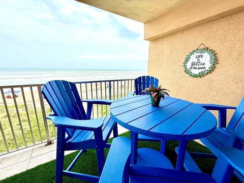 Oceanfront private balcony with blue Adirondack chairs and `Life is Better on the Porch` sign.
