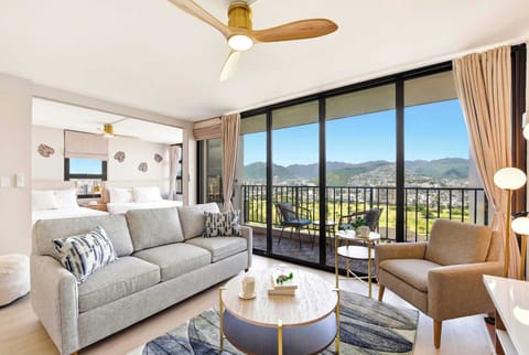 Your living area features chic, comfortable seating and expansive floor-to-ceiling glass doors that reveal a private balcony with sweeping mountain views.