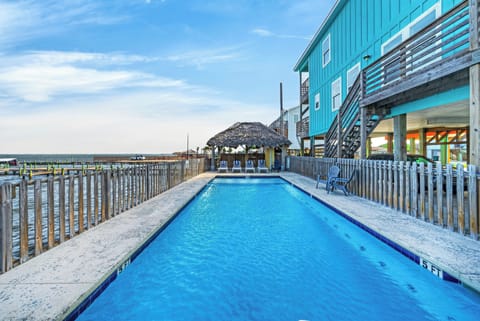 Waterfront pool with bay views, lounge seating, and a tiki-style shaded area for relaxing by the water.