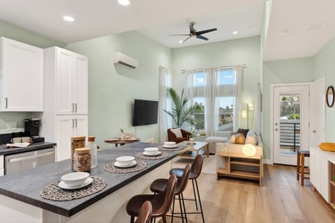 Bright open-concept kitchen and living area with island seating, airy ceilings, and balcony access.