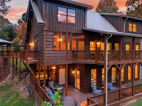 Warm mountain retreat with multiple covered decks, glowing interiors, and cozy cabin charm at sunset.