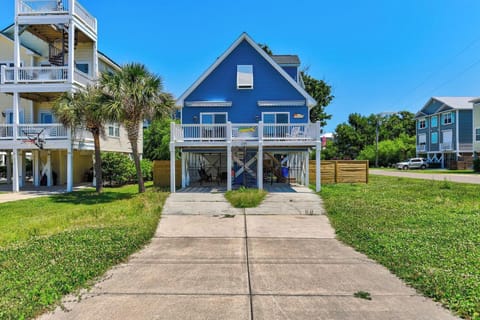 Charming blue coastal property with elevated deck and palm-lined entrance, nestled in a peaceful beachside neighborhood offering easy access to local attractions.