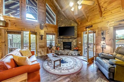 Your cozy log cabin retreat awaits with soaring ceilings, stone fireplace, and forest views from every window.
