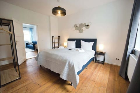 Schlafzimmer mit Doppelbett, im Hintergrund der Blick ins Wohnzimmer