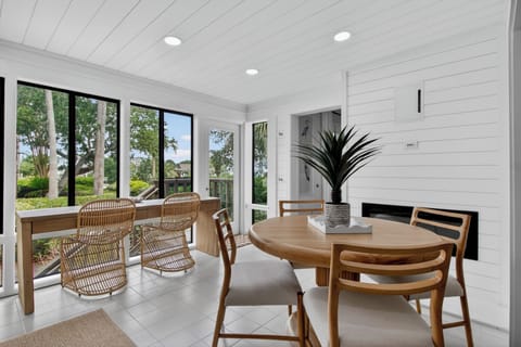 Enjoy morning coffee at your private dining table as sunlight streams through floor-to-ceiling windows, framing peaceful garden views and inviting breezes from the adjacent patio.