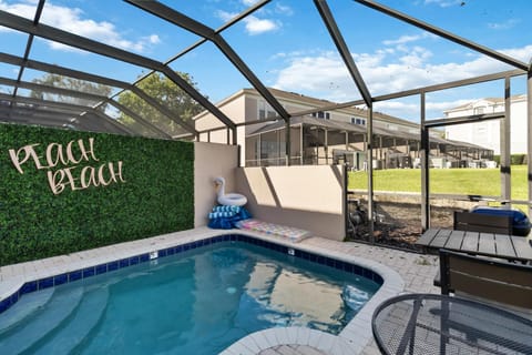 Private screened pool area with a tiled edge, greenery wall sign, inflatable float, and outdoor seating.