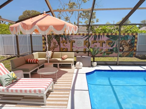 Screened private pool with stylish lounge seating and tropical mural