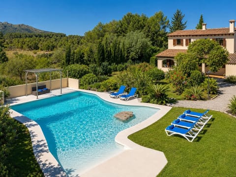 A luxurious villa garden with a large private pool, lush greenery, and mountain views.